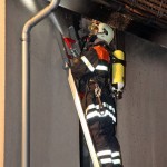 Ein Feuerwehrangehöriger beim Kühlen des Daches auf der Steckleiter